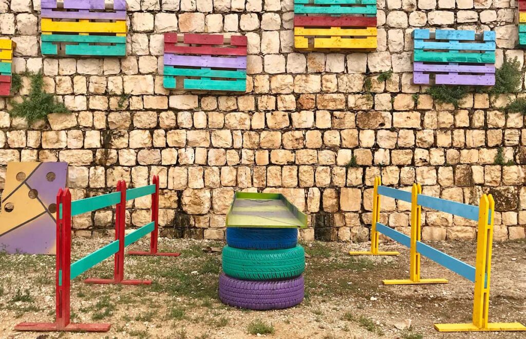 a colorful fence and tires in front of a stone wall