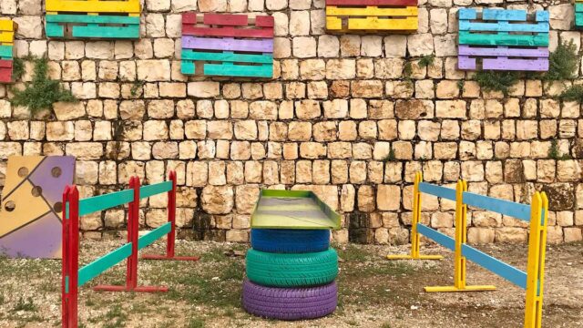 a colorful fence and tires in front of a stone wall