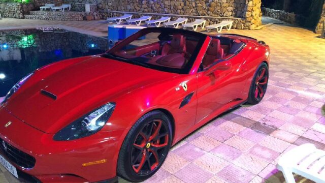 a red sports car parked next to a pool