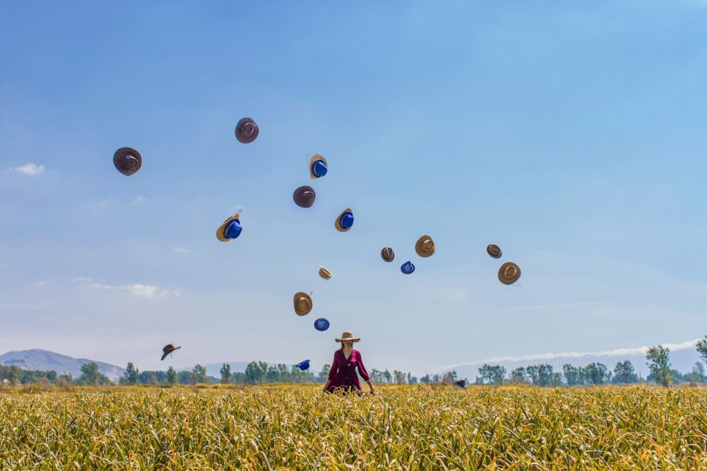 a woman in a field with hats in the air