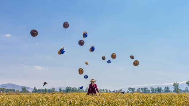 a woman in a field with hats in the air