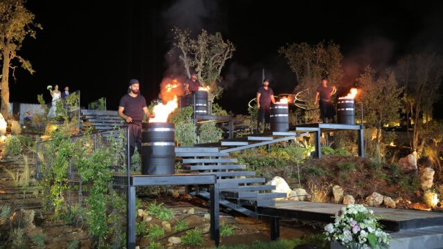 a group of people standing on a set of metal barrels with fire