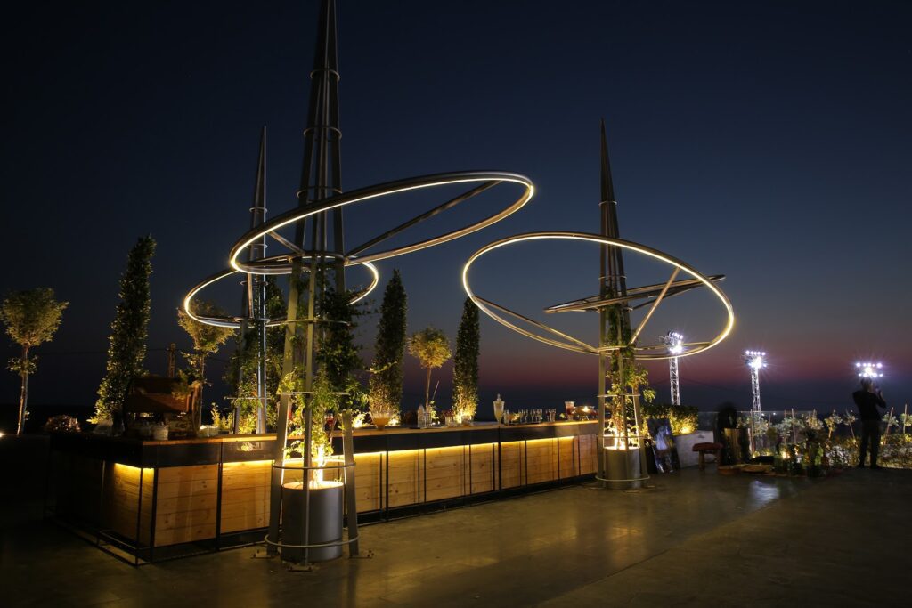 a rooftop bar with a group of trees and a building with lights