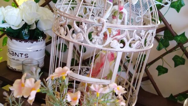 a white bird cage with pink flowers