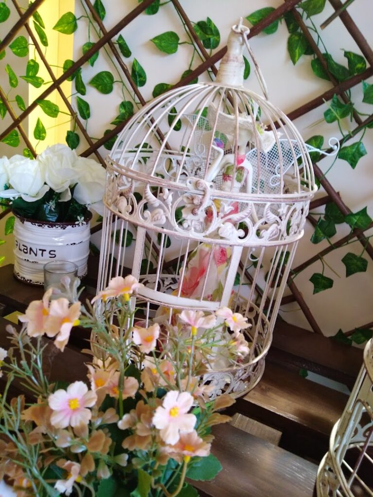 a white bird cage with pink flowers