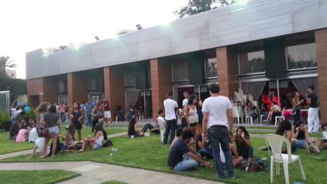 a group of people sitting on grass outside a building