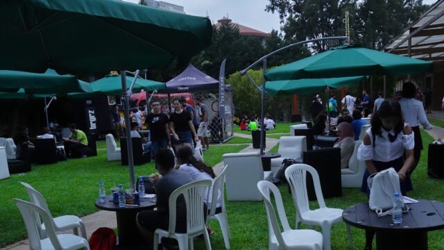 a group of people sitting at tables and chairs in a park