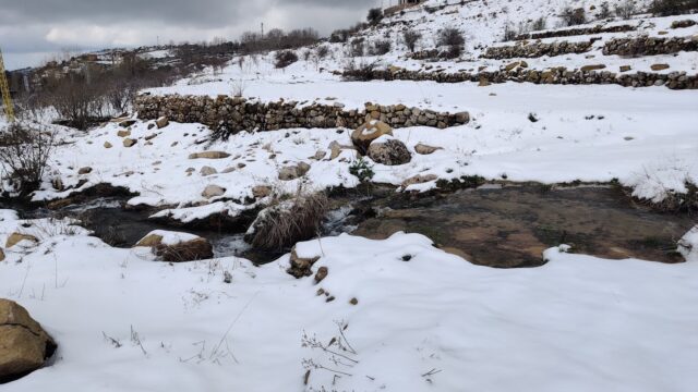 a snowy landscape with a stream