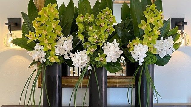 a group of flowers in black vases on a table