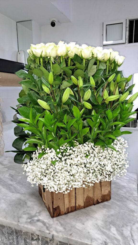 a group of white roses and baby's breath in a wooden box