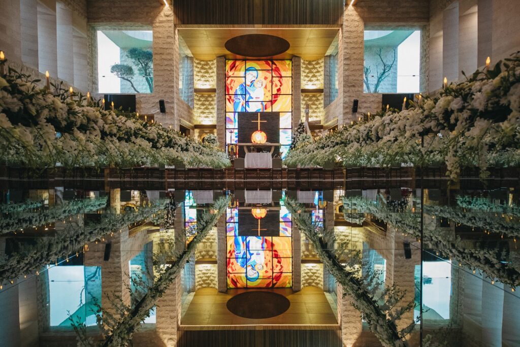 a reflection of a church with flowers and a stained glass window