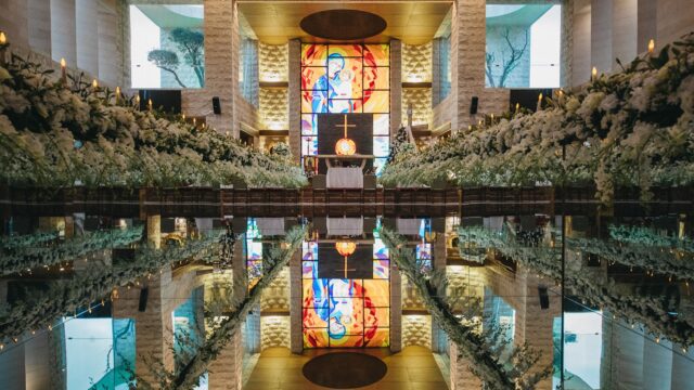 a reflection of a church with flowers and a stained glass window