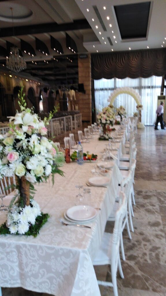 a long table with white chairs and flowers