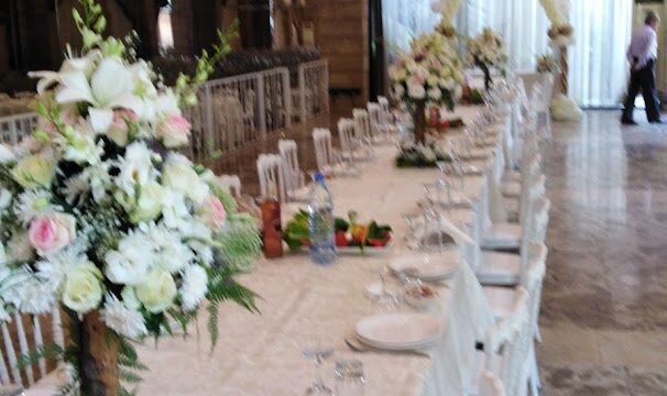 a long table with white chairs and flowers