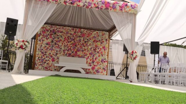 a white tent with flowers on the wall and white chairs