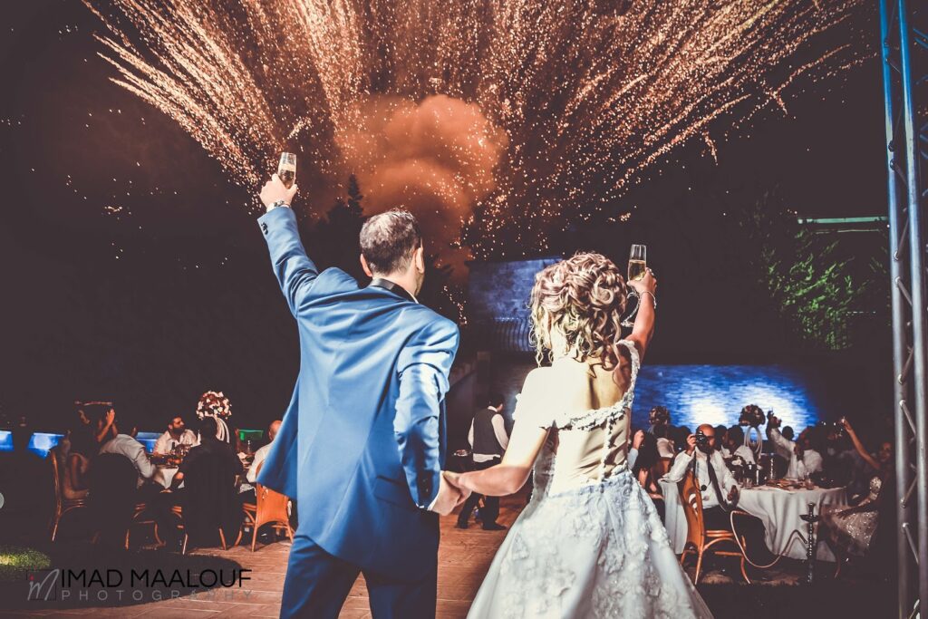 a man and woman holding hands and dancing with fireworks in the background