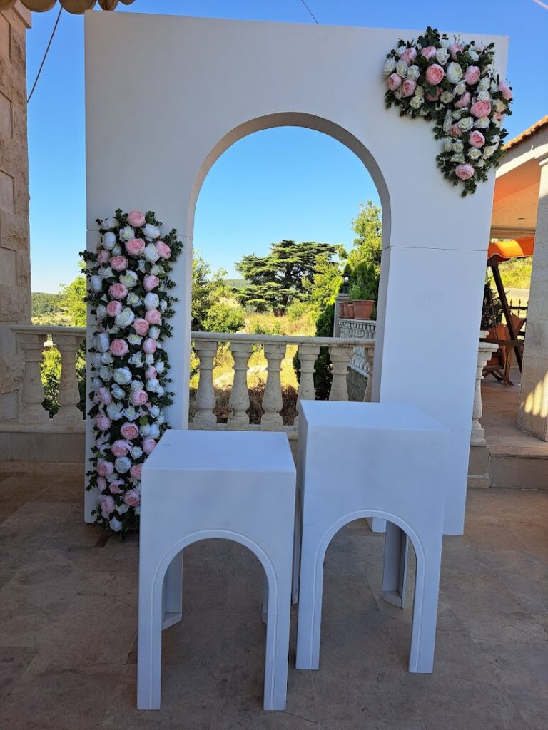 A white archway with flowers on it, decorated by JJ's Event Planner.