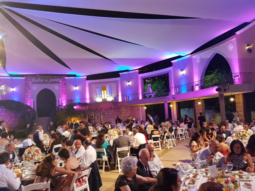 a large group of people sitting at tables in a room with purple lights