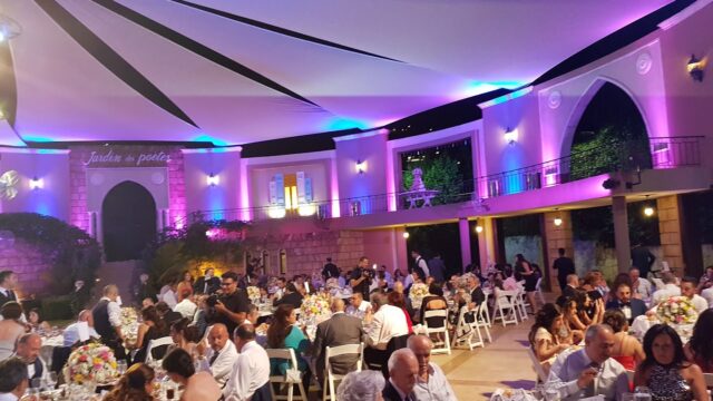 a large group of people sitting at tables in a room with purple lights