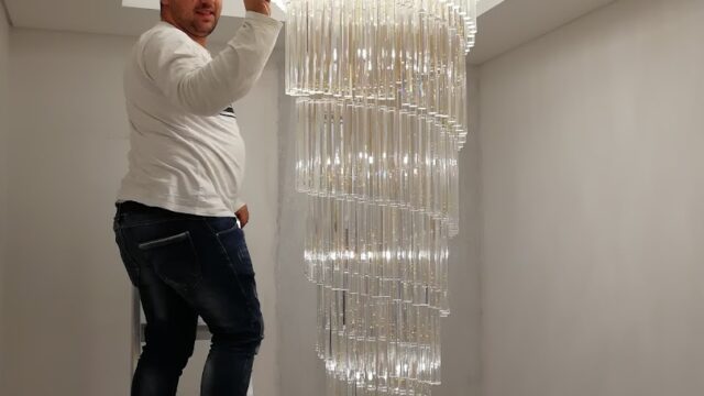 a man standing on a ladder on a ladder holding a chandelier