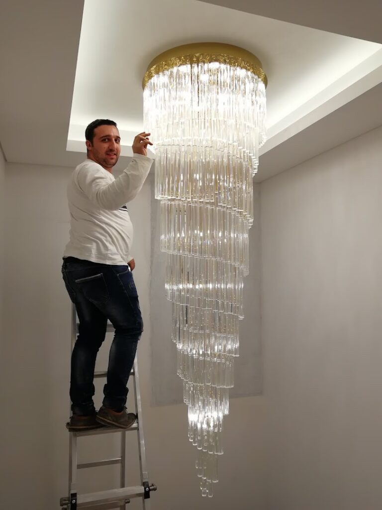 a man standing on a ladder on a ladder holding a chandelier