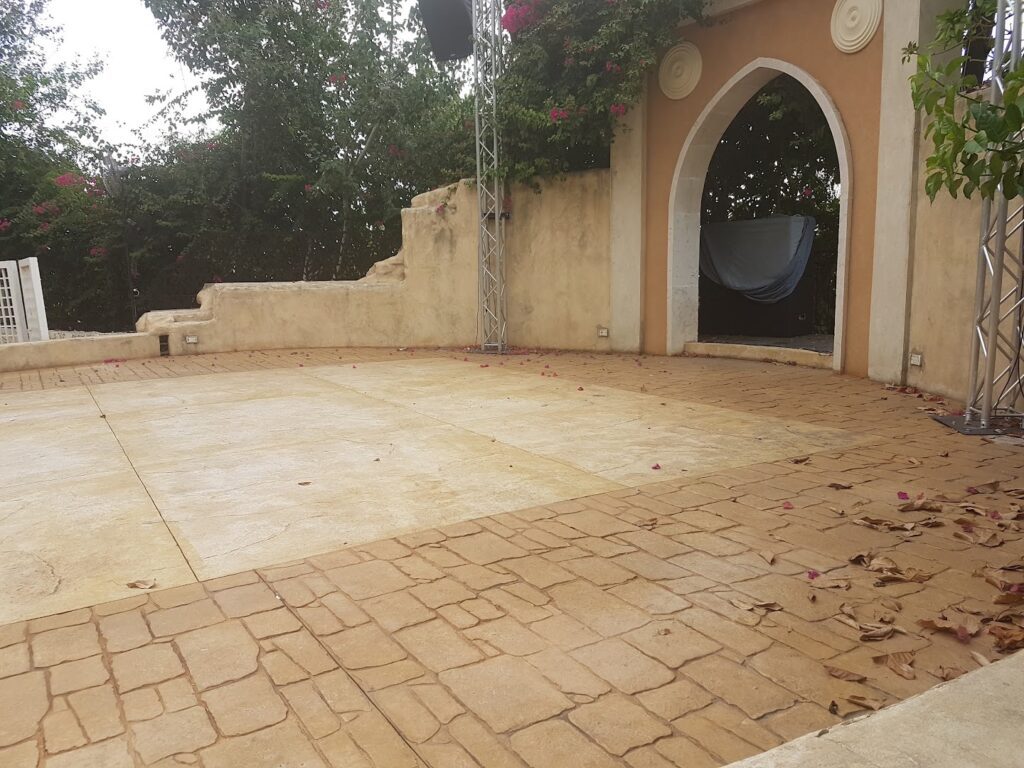 a stone patio with a stone arch and a metal pole