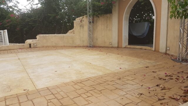 a stone patio with a stone arch and a metal pole