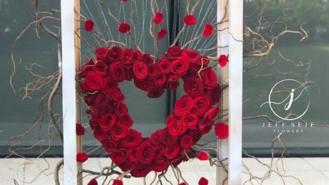 a heart shaped flower arrangement in a white frame