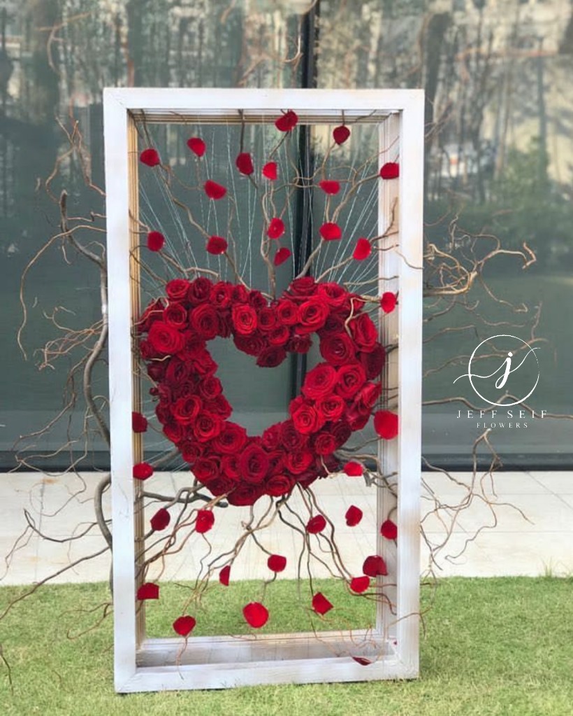 a heart shaped flower arrangement in a white frame