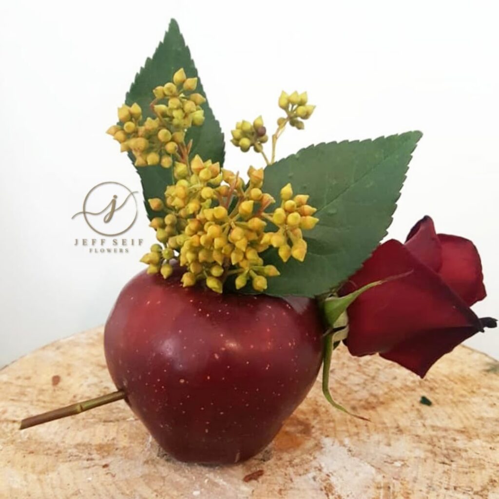 a red apple with a rose and leaves on it