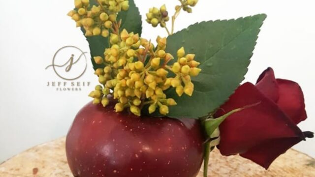 a red apple with a rose and leaves on it