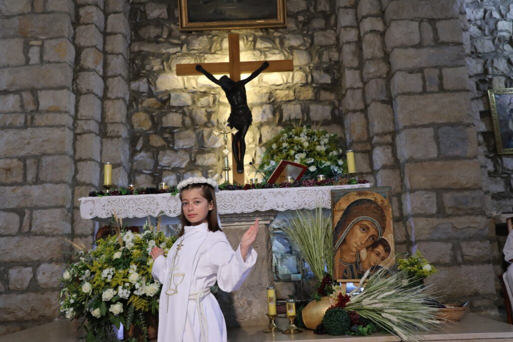 a girl in a white robe in front of a cross