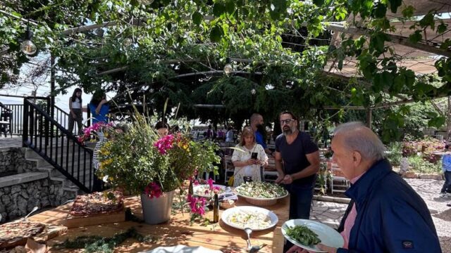 a group of people standing around a table with food