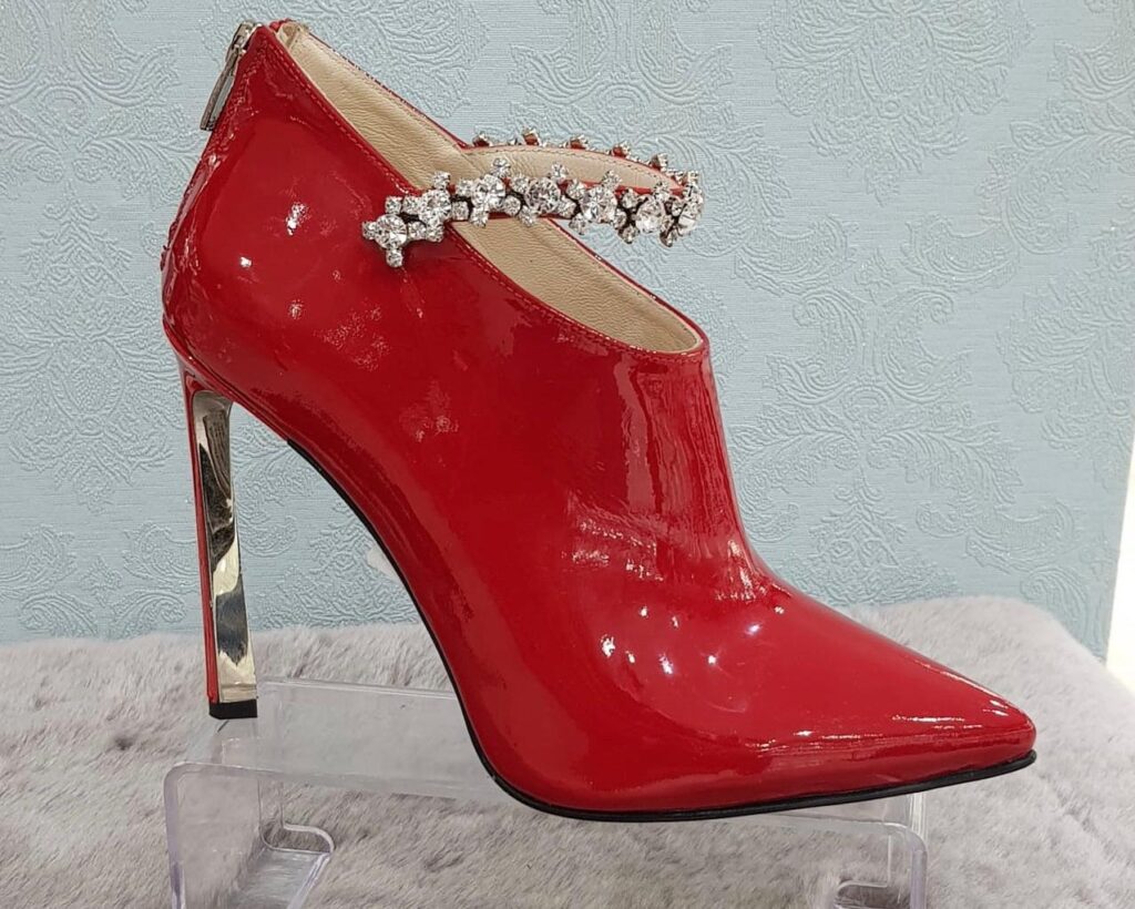 a red high heeled shoe with a jewel on the side