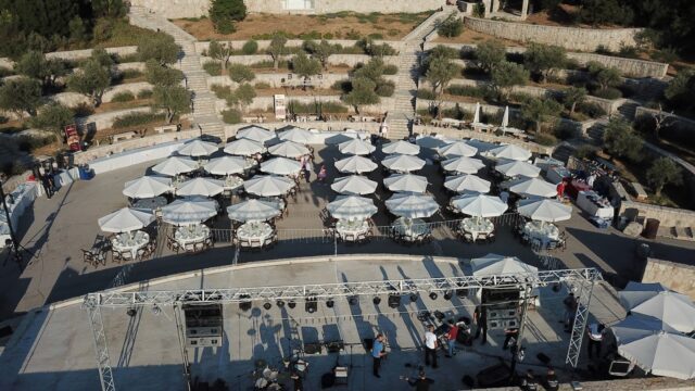 an aerial view of a stage with white umbrellas and people