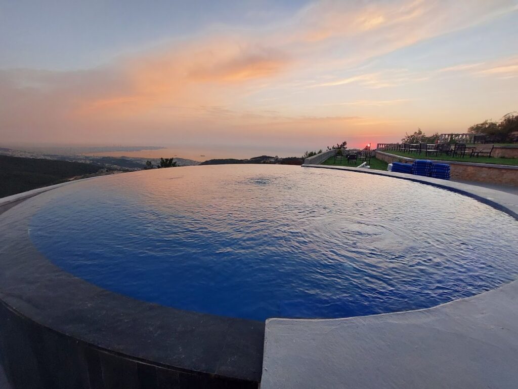 a pool with a view of the ocean and a sunset