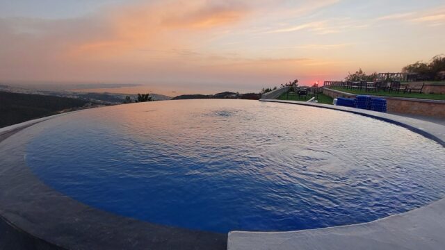 a pool with a view of the ocean and a sunset