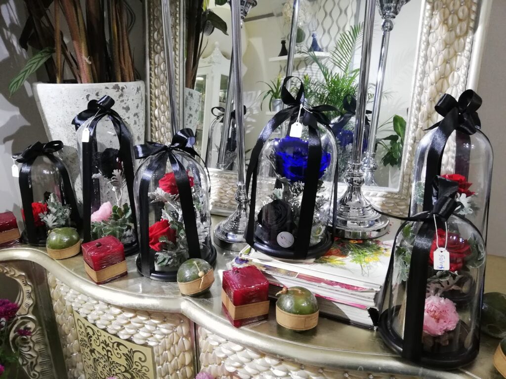 a group of glass bell jars with flowers and a black ribbon on a table