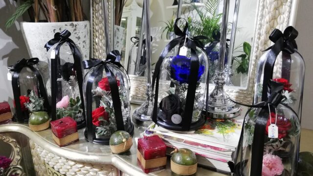 a group of glass bell jars with flowers and a black ribbon on a table