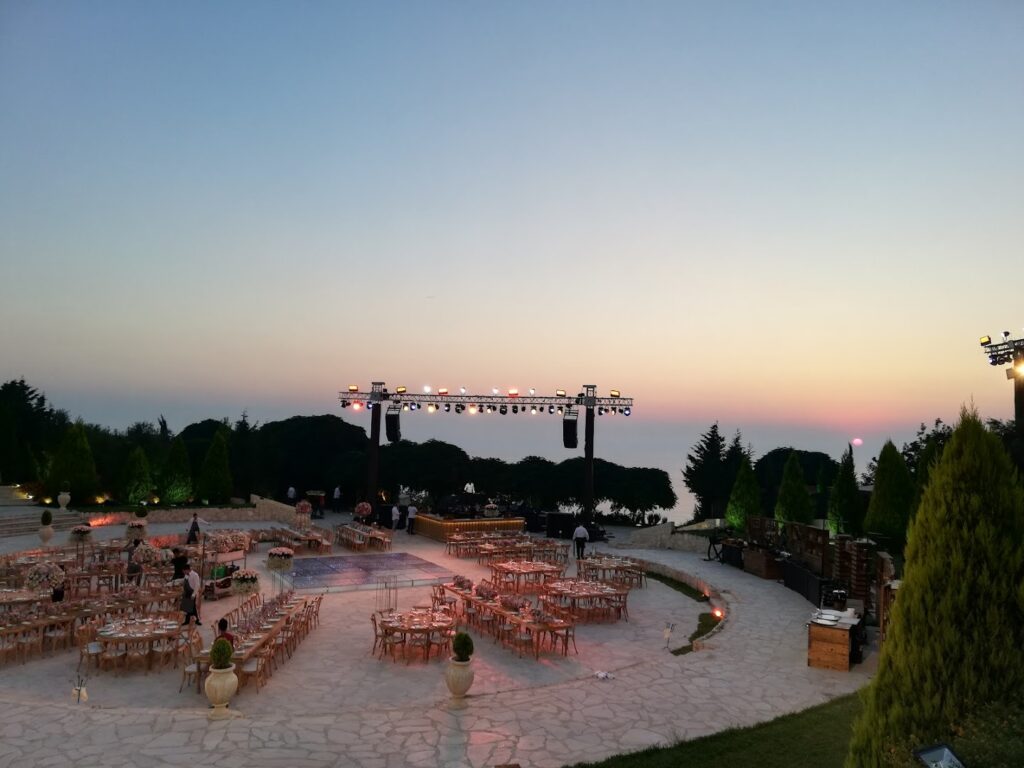 a group of tables and chairs in a circular area with a stage and trees