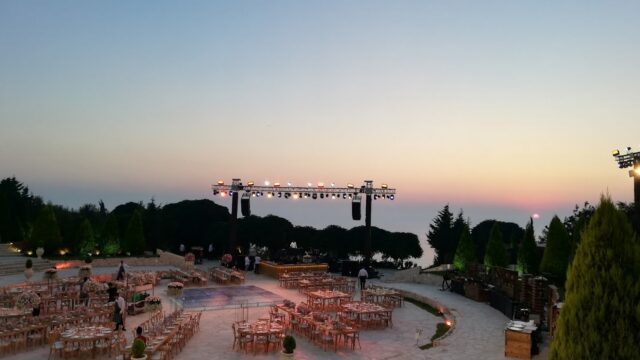 a group of tables and chairs in a circular area with a stage and trees