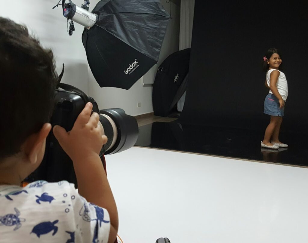 a child taking a picture of a girl in a photo studio
