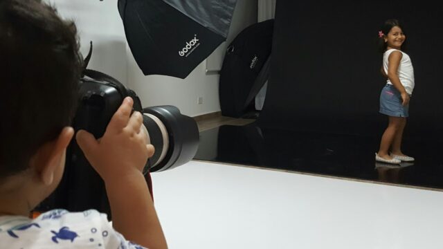 a child taking a picture of a girl in a photo studio