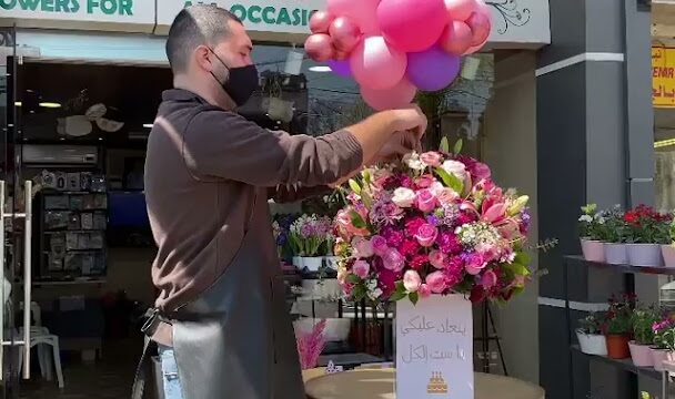 a man wearing a face mask holding a bunch of balloons