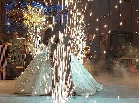 a couple in wedding dresses dancing with fireworks