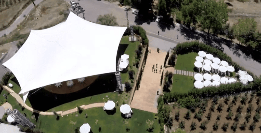 a large white tent with white umbrellas and green grass