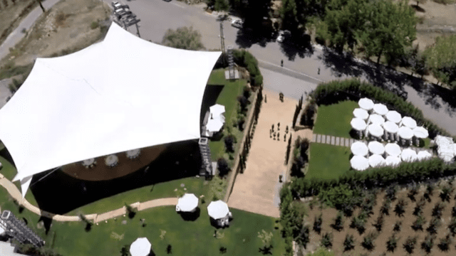 a large white tent with white umbrellas and green grass