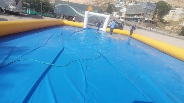 a large inflatable pool with people standing in front of a mountain