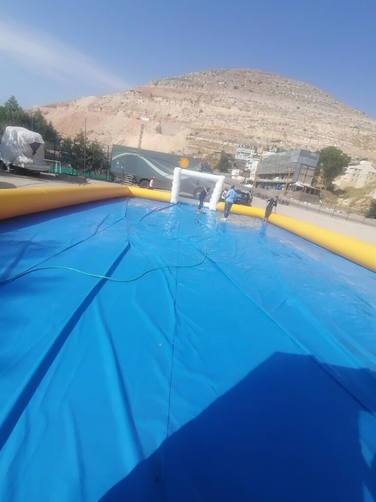 a large inflatable pool with people standing in front of a mountain