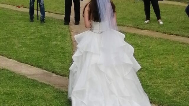 a woman in a wedding dress walking down a path